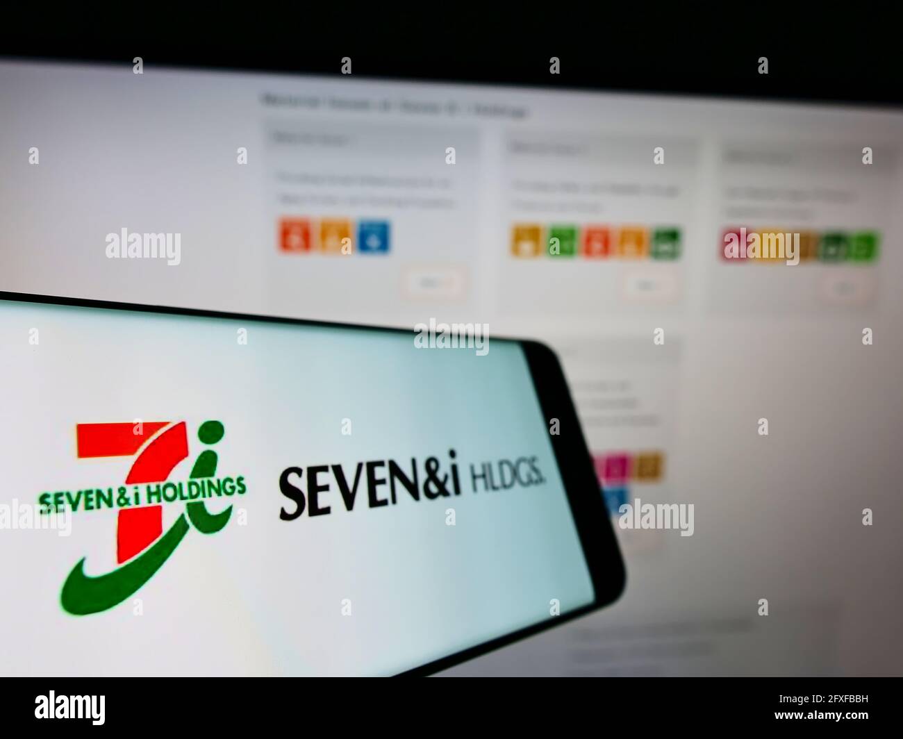 Téléphone mobile avec le logo de la société japonaise de détail Seven et i Holdings Co. Ltd. À l'écran devant le site Web. Mise au point au centre-gauche de l'écran du téléphone. Banque D'Images