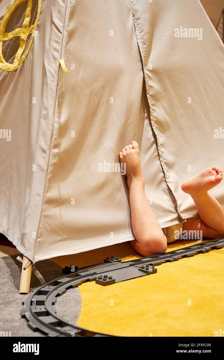 Petit garçon jouant et dormant dans la cabane à jouets avec ses jouets et son chemin de fer. Activités de loisirs d'enfance et intérieurs confortables Banque D'Images