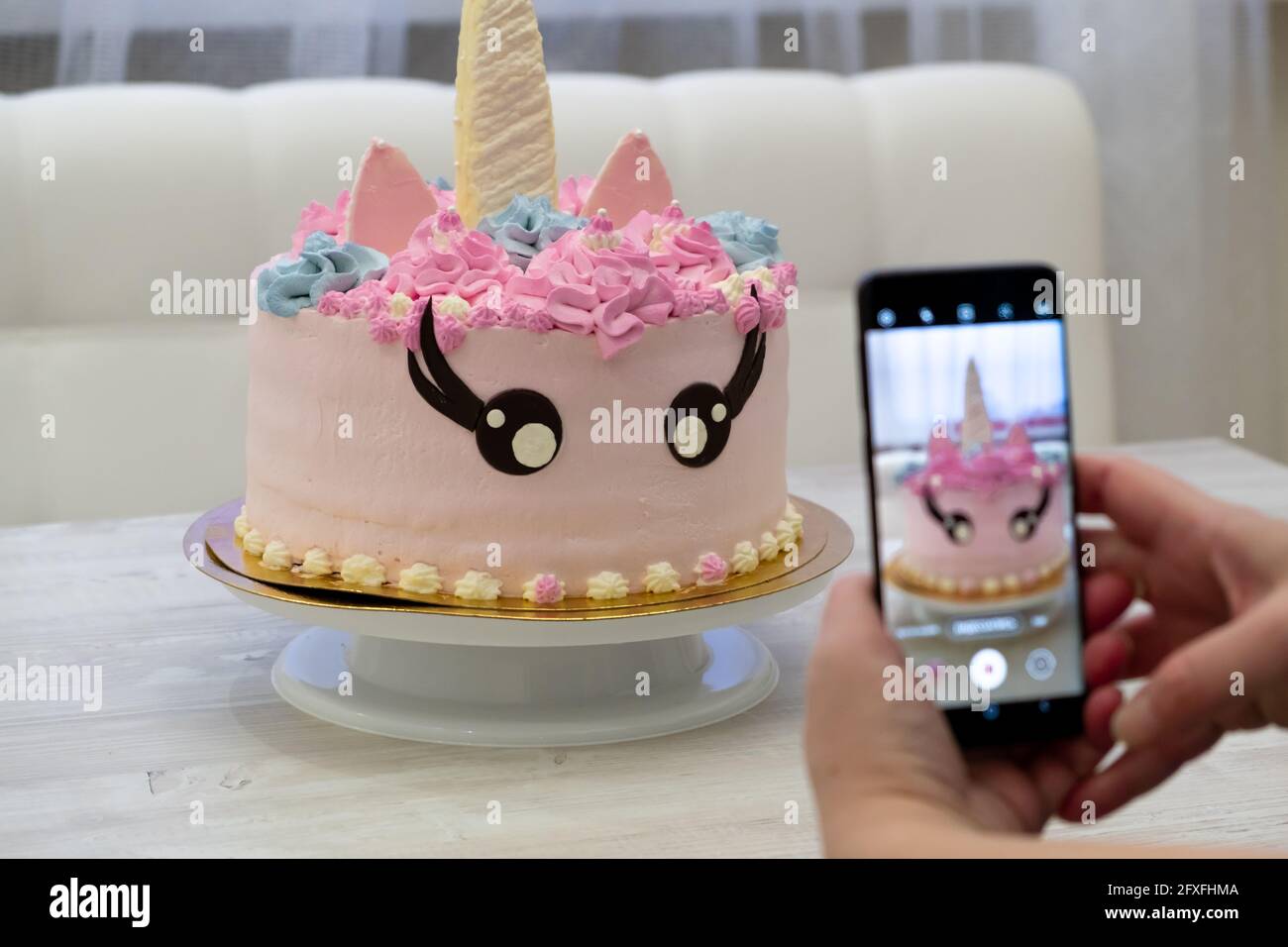 Main Feminine Prend Une Photo Sur Un Smartphone Un Anniversaire Gateau Sous Forme De Licorne Rose Pour Chats Photo Stock Alamy