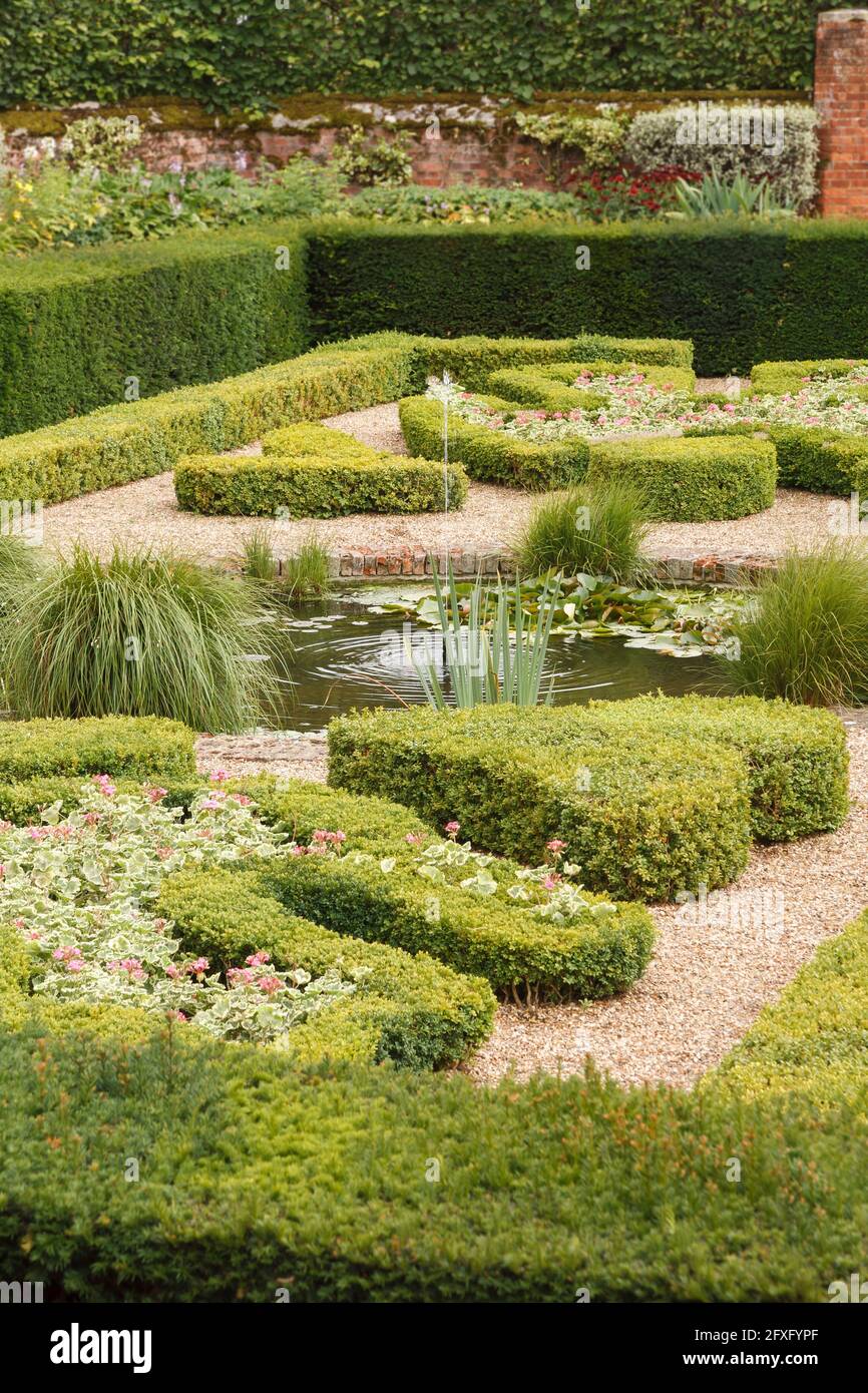 Haie tronquée (buxus) dans un jardin anglais géométrique formel avec étang et fontaine, Royaume-Uni Banque D'Images