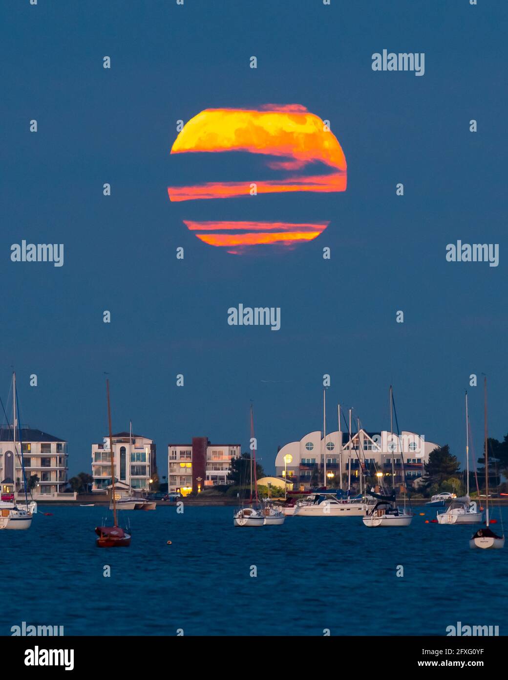 Poole, Dorset, Royaume-Uni. 26 mai 2021. Météo Royaume-Uni. La pleine fleur super lune est obscurcie par les nuages comme il s'élève de derrière millionnaires rangée à Sandbanks à Poole dans Dorset. Crédit photo : Graham Hunt/Alamy Live News Banque D'Images