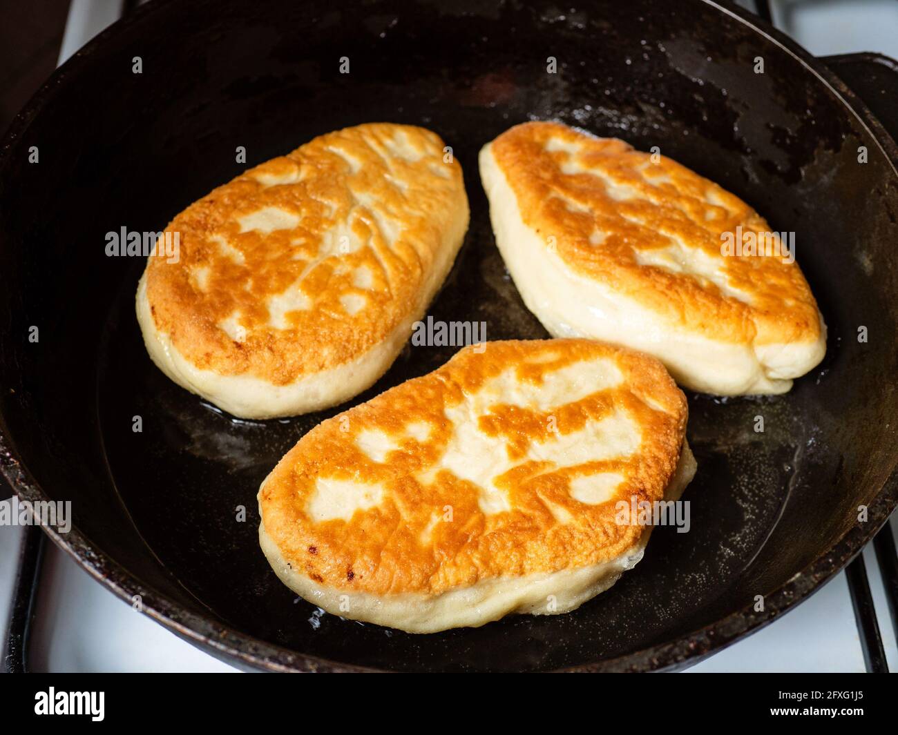 cuisson de tartes avec purée de pommes de terre à la cuisine maison - un les tourtes fourrées frites sur le côté friture dans l'huile dans la poêle Banque D'Images