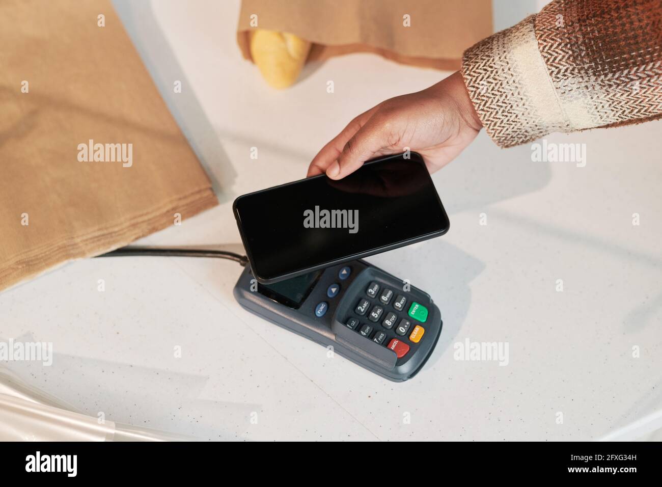 Gros plan de la femme utilisant le téléphone mobile et payant en ligne par terminal dans la boutique Banque D'Images