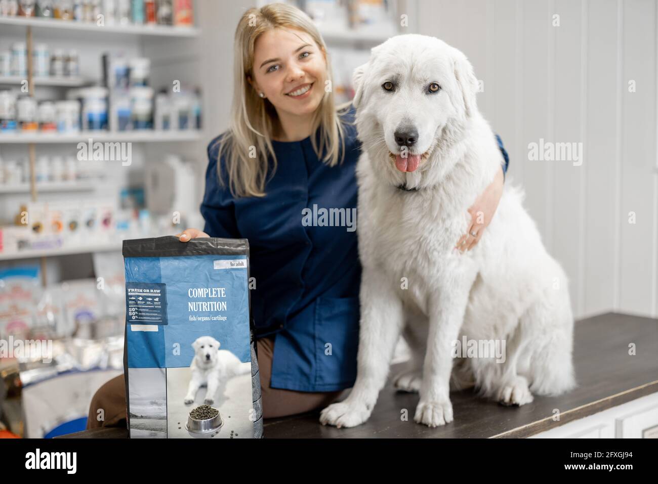 Un portrait de femme gaie vétérinaire et grand chien de berger assis à la réception du magasin vétérinaire et de la clinique. Soins et traitement pour animaux de compagnie. Nourriture sèche et nutrition pour chiens. Banque D'Images
