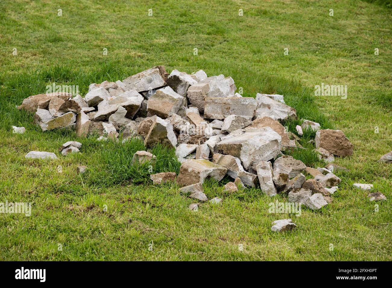 Morceaux de béton cassés sur une herbe verte Banque D'Images