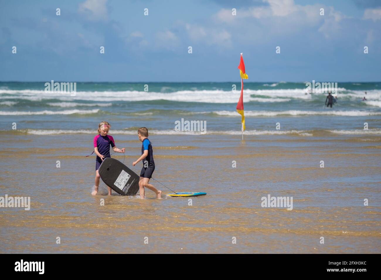 Mawgan Porth Beach à Cornwall, Royaume-Uni; jeunes enfants jouant en mer avec leurs planches de corps; vacances de canication cornouailles au Royaume-Uni. Banque D'Images