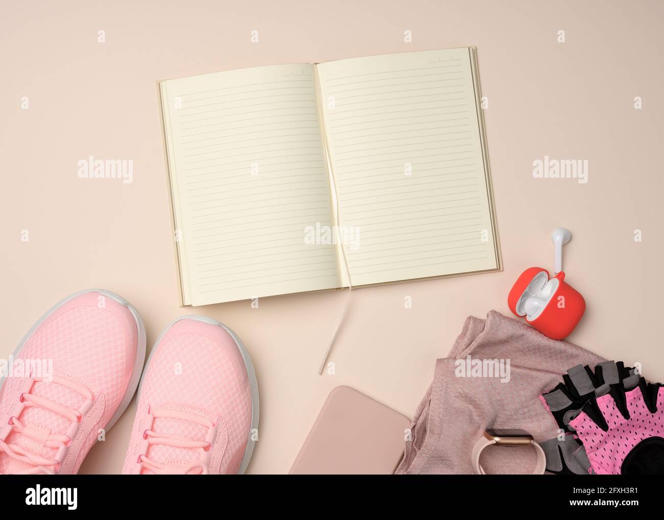 carnet ouvert avec pages vierges, baskets roses et gadgets intelligents sur fond beige. Place pour enregistrer les objectifs et les réalisations, le calendrier, la mise en plan Banque D'Images