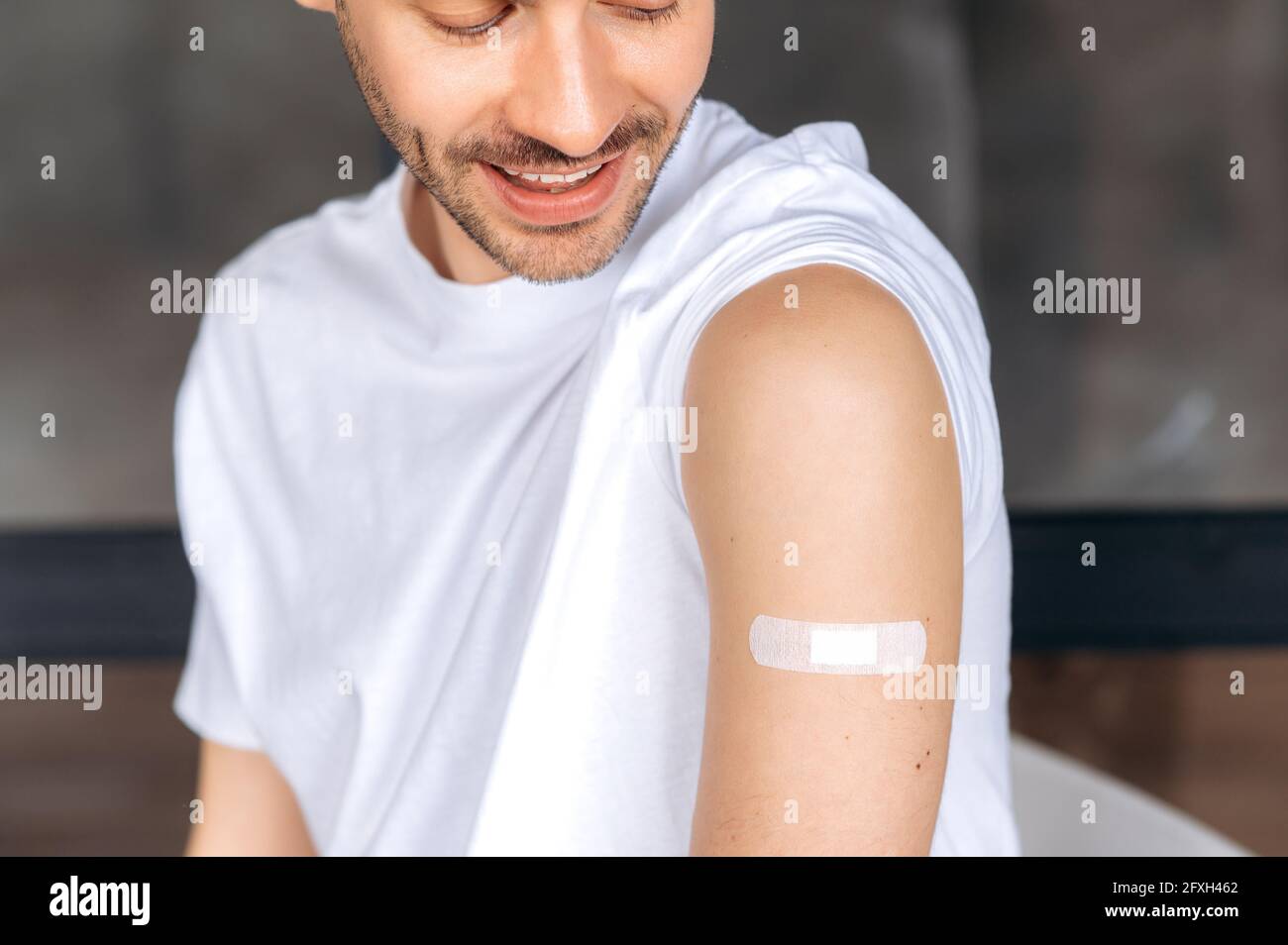 Vaccination. Un jeune homme caucasien en bonne santé, vêtié de vêtements décontractés et d'aide-bandeau sur son épaule, a reçu le vaccin contre le covid 19 ou la grippe, l'immunité contre les virus et les infections, prend soin de sa santé Banque D'Images
