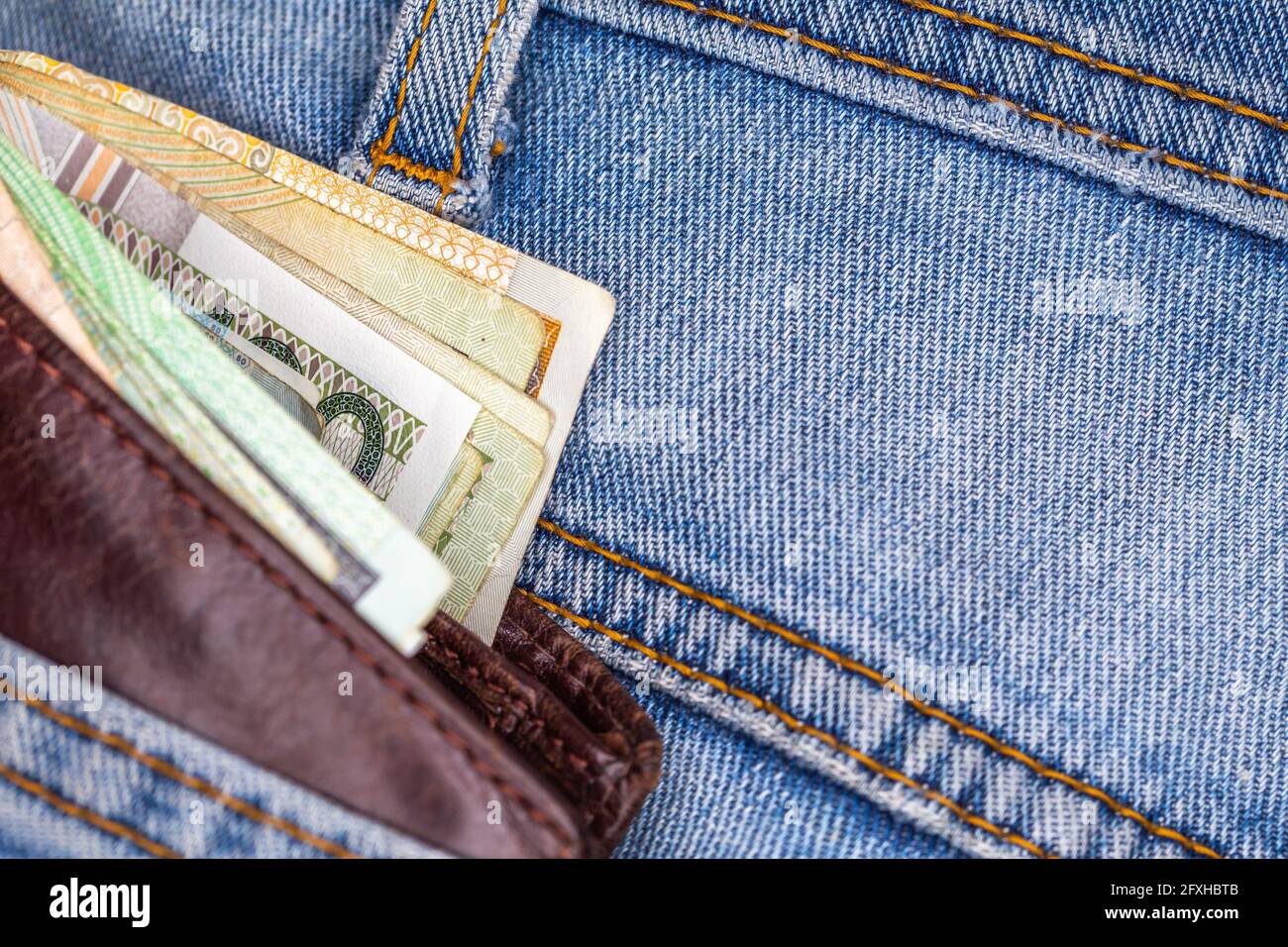 Portefeuille et beaucoup de billets polonais sortant de la poche arrière du pantalon en denim. Photo prise sous une lumière artificielle douce Banque D'Images
