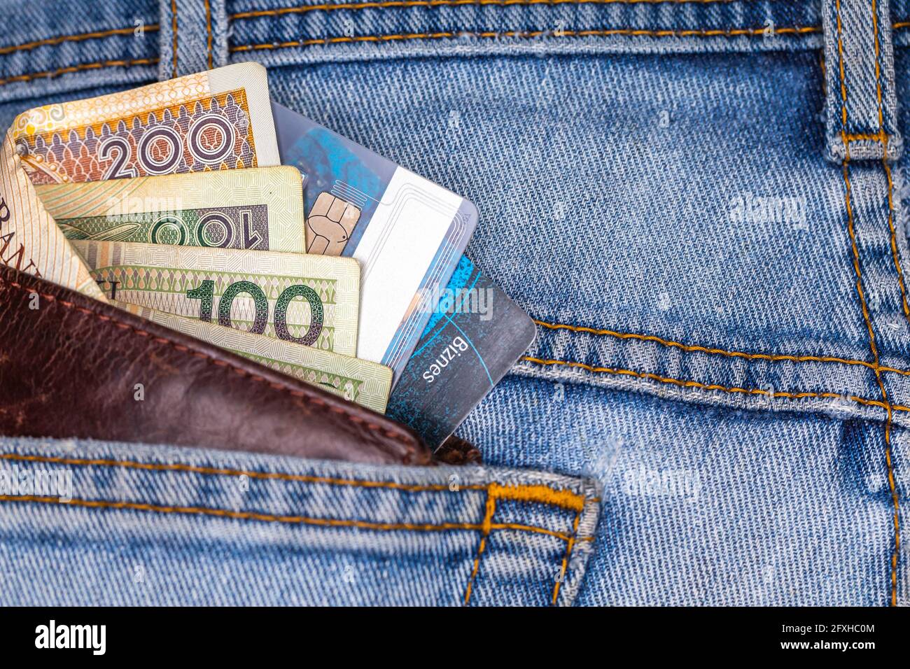 Portefeuille et beaucoup de billets polonais sortant de la poche arrière du pantalon en denim. Photo prise sous une lumière artificielle douce Banque D'Images