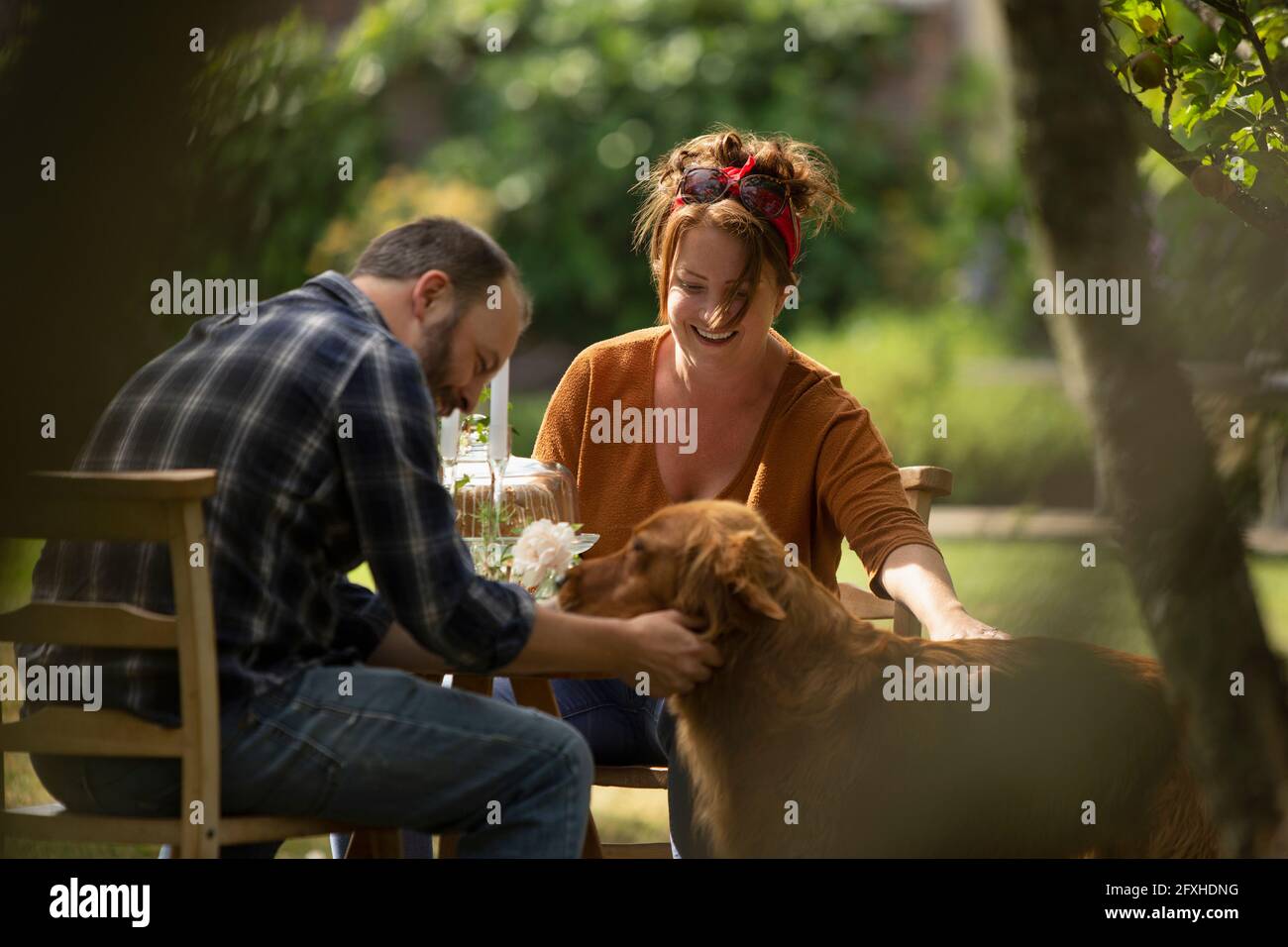 Couple heureux avec chien Golden Retriever à la table du jardin Banque D'Images