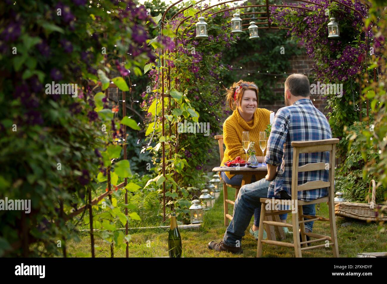 Couple heureux en train de déguster du champagne dans un jardin d'été idyllique Banque D'Images Couple heureux en train de déguster du champagne dans un jardin d'été idyllique Banque D'Images