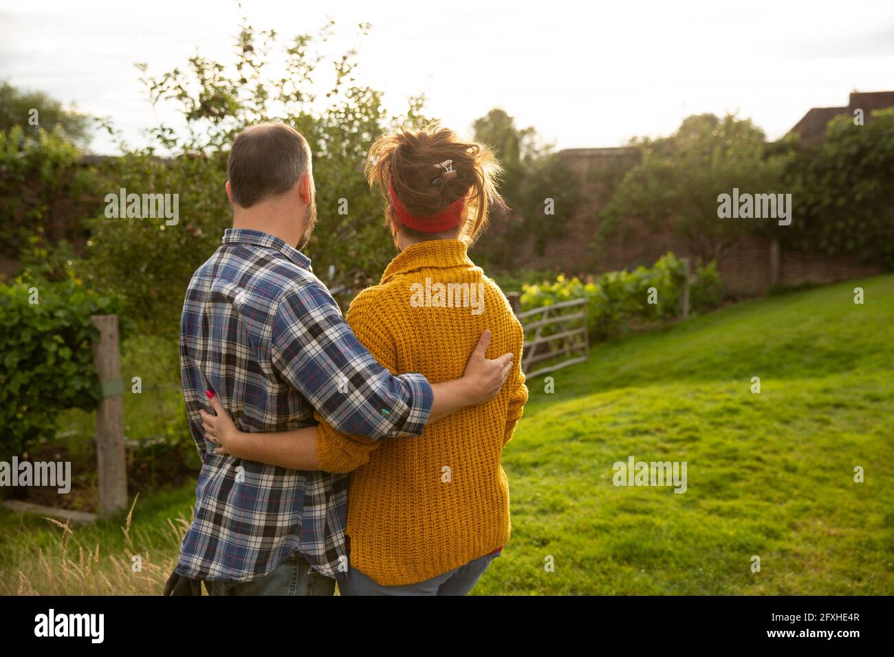 Couple heureux qui s'embrasse dans un jardin d'été ensoleillé Banque D'Images Couple heureux qui s'embrasse dans un jardin d'été ensoleillé Banque D'Images