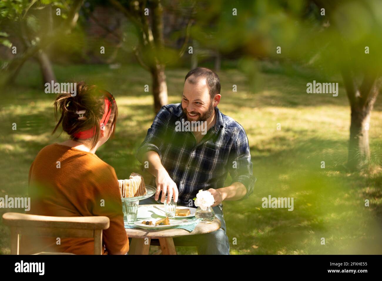 Couple heureux en train de déguster un gâteau à la table du jardin d'été Banque D'Images Couple heureux en train de déguster un gâteau à la table du jardin d'été Banque D'Images