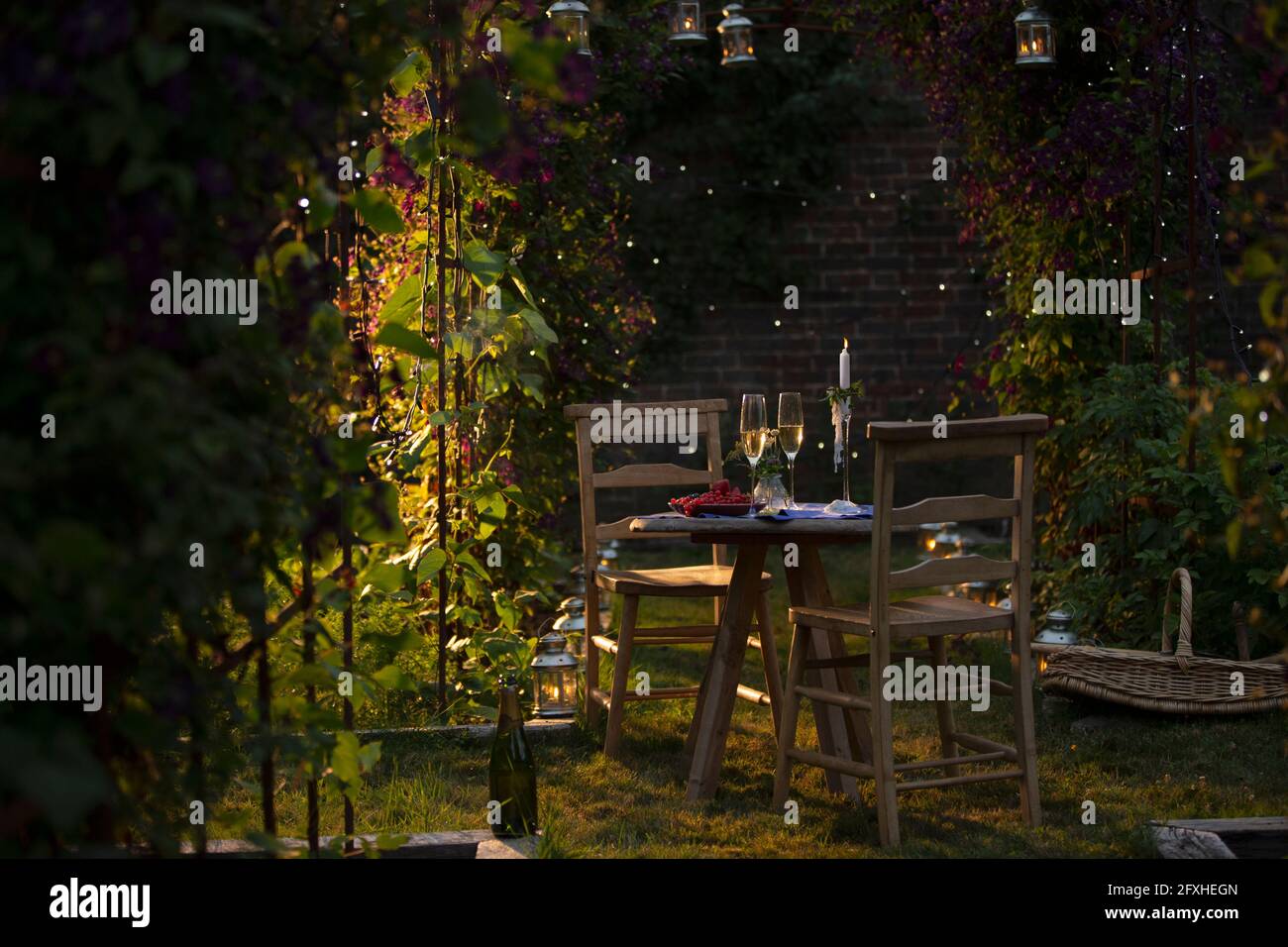 Champagne et raisins de Corinthe rouges sur une table de jardin d'été idyllique Banque D'Images