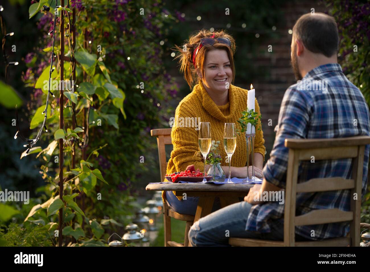 Couple heureux en train de déguster du champagne à la table du jardin Banque D'Images