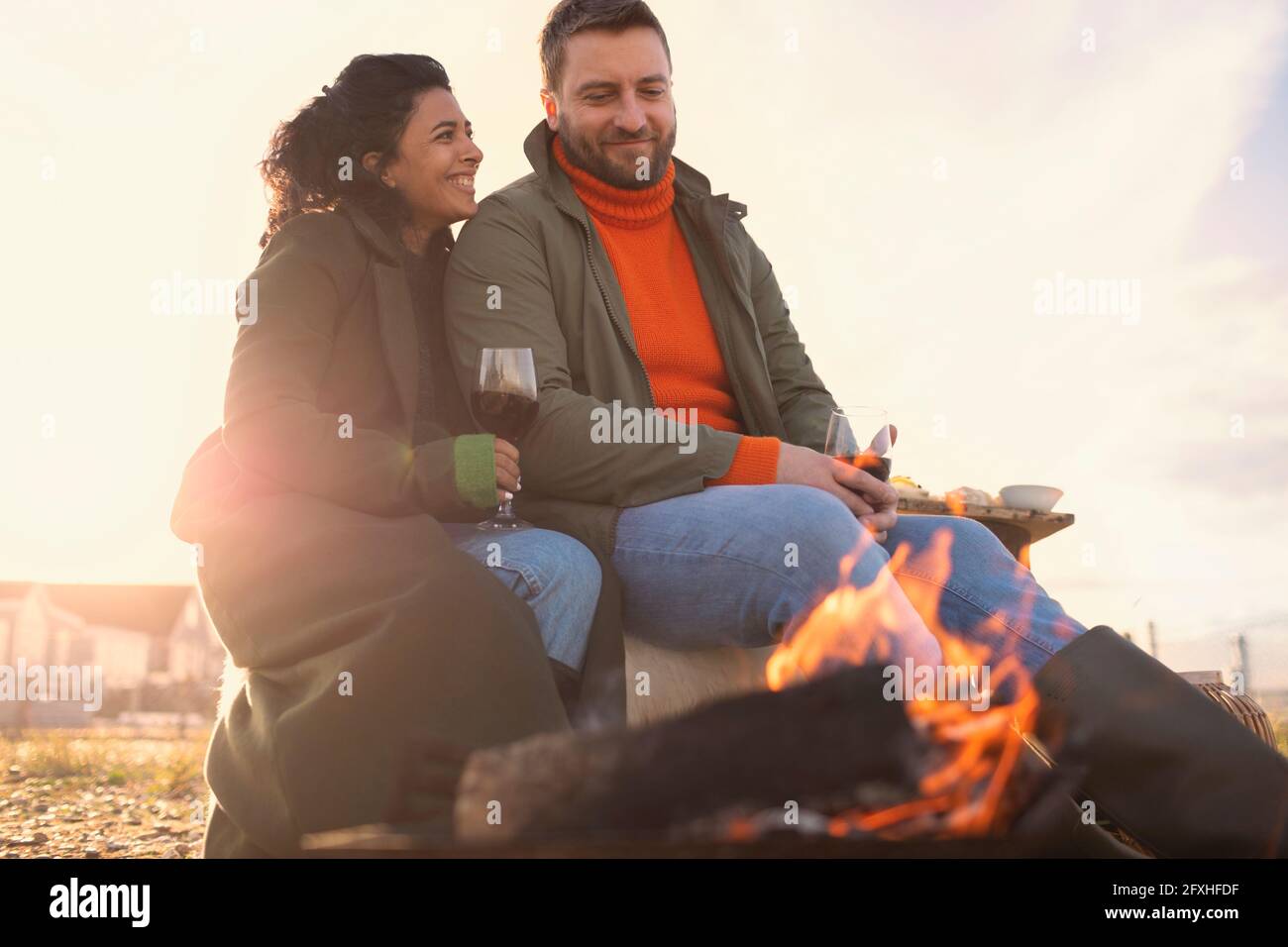 Couple heureux en appréciant le vin rouge au feu sur la plage d'hiver Banque D'Images