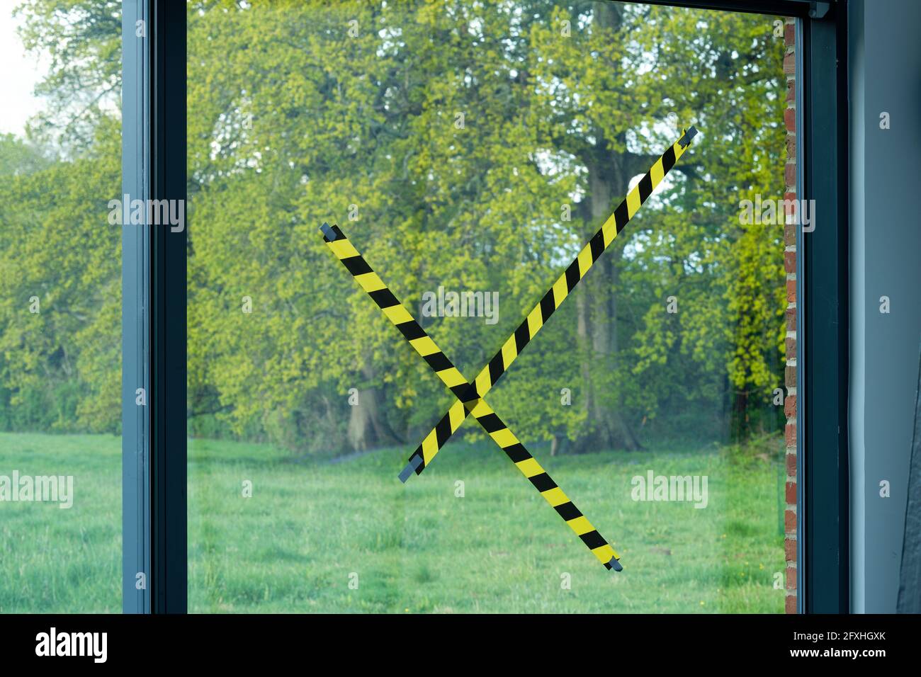 Ruban adhésif collé sur une fenêtre en verre pour empêcher les enfants et les adultes de s'y cogner. Ruban de sécurité pour réduire les risques de grandes vitres en verre transparent. Banque D'Images