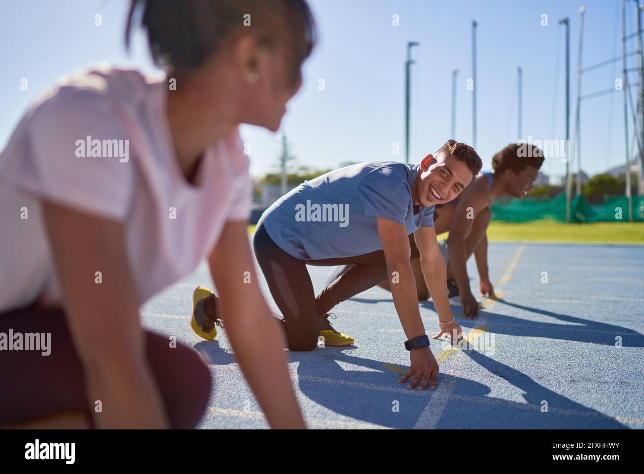 Les coureurs heureux à la ligne de départ sur la piste de sport ensoleillée Banque D'Images