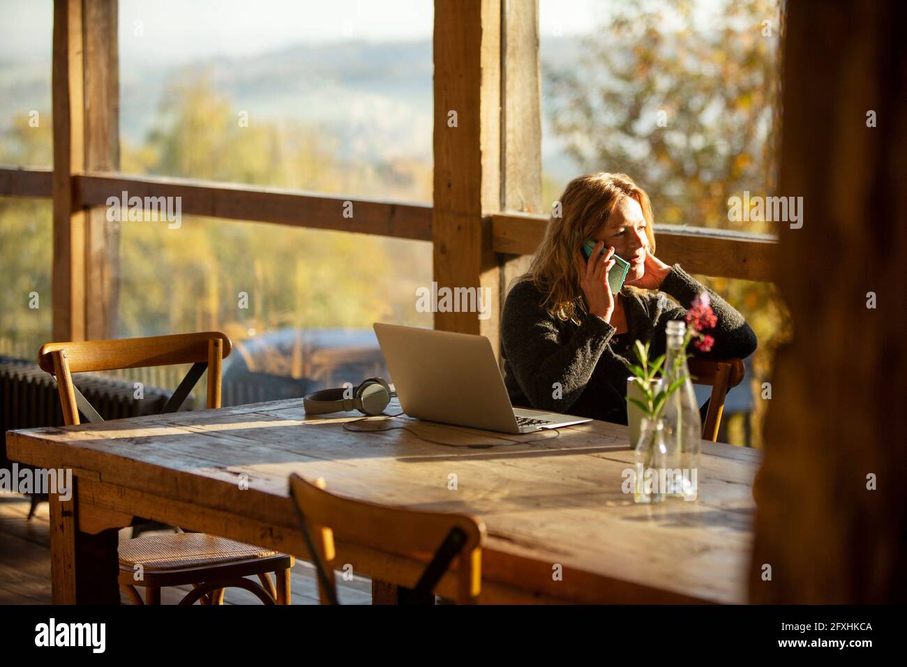 Femme d'affaires parlant au téléphone au portable dans un restaurant ensoleillé Banque D'Images