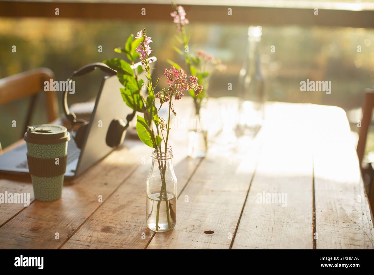 Arrangement simple de fleurs sauvages en bouteille de verre sur table rustique de café Banque D'Images