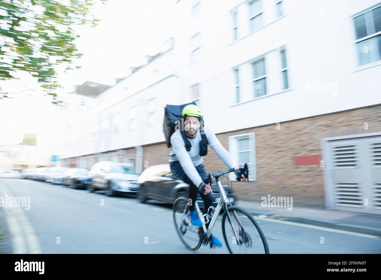 Un messager à vélo masculin qui fournit de la nourriture dans la rue urbaine Banque D'Images