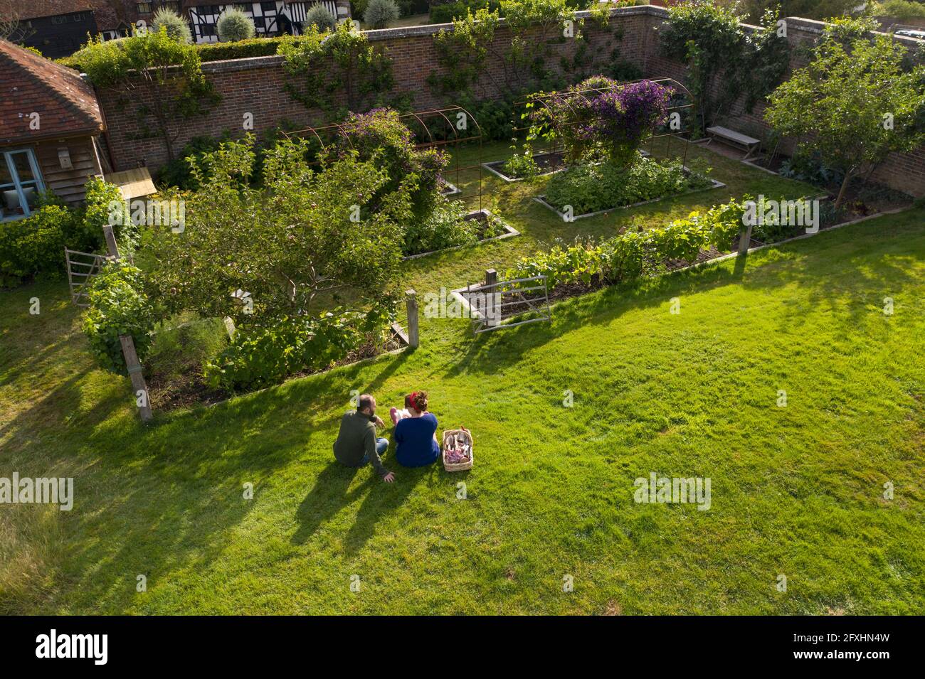 Couple en train de faire une pause dans un jardin luxuriant idyllique et ensoleillé Banque D'Images