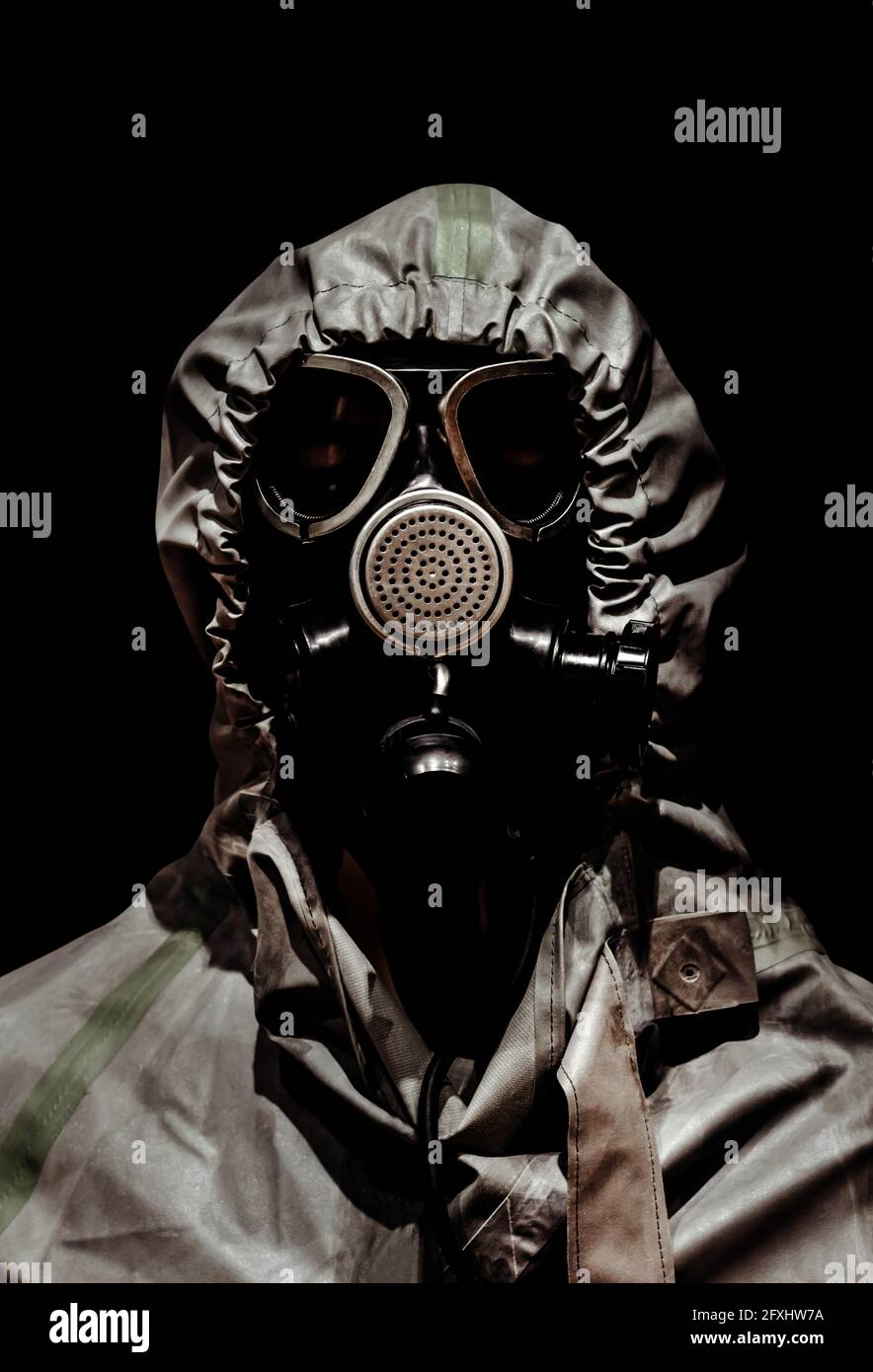 Photo d'un homme en masque de protection chimique en caoutchouc et combinaison de corps sur fond noir. Banque D'Images