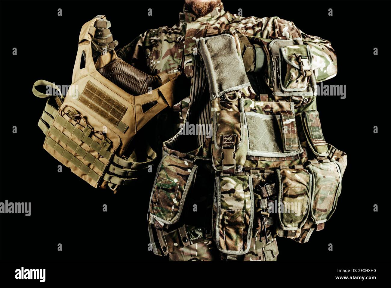 Photo d'un soldat portant différents types de gilets blindés camoufés sur fond noir. Banque D'Images