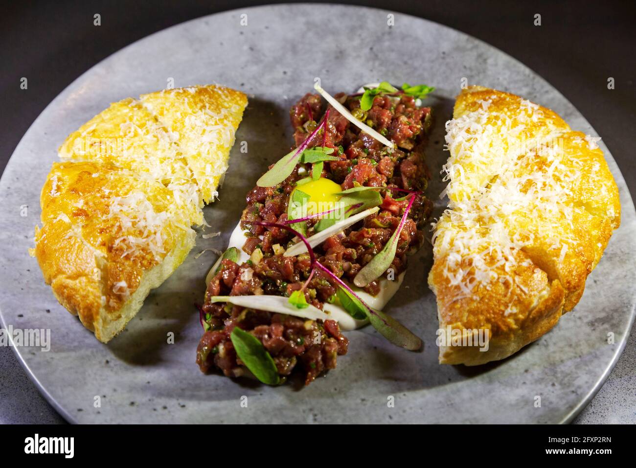 Steak tartare servi avec du pain foccacia de style italien. Le plat est fait avec du bœuf cru, du jaune d'œuf et d'autres ingrédients frais. Banque D'Images