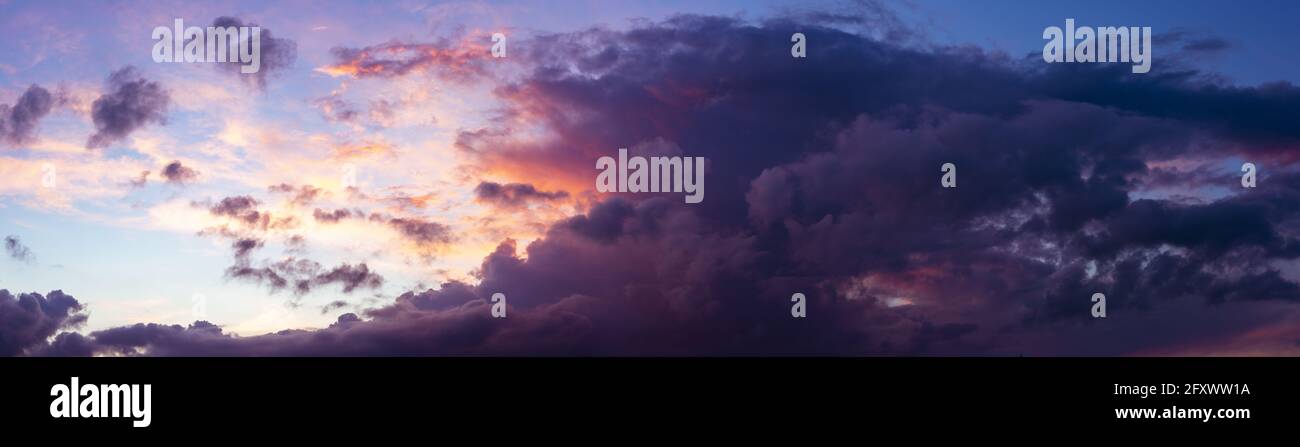 Vue panoramique avec ciel bleu vif et coucher de soleil spectaculaire contrastant les couleurs jaune, rouge et orange touchant le cumulus. Banque D'Images