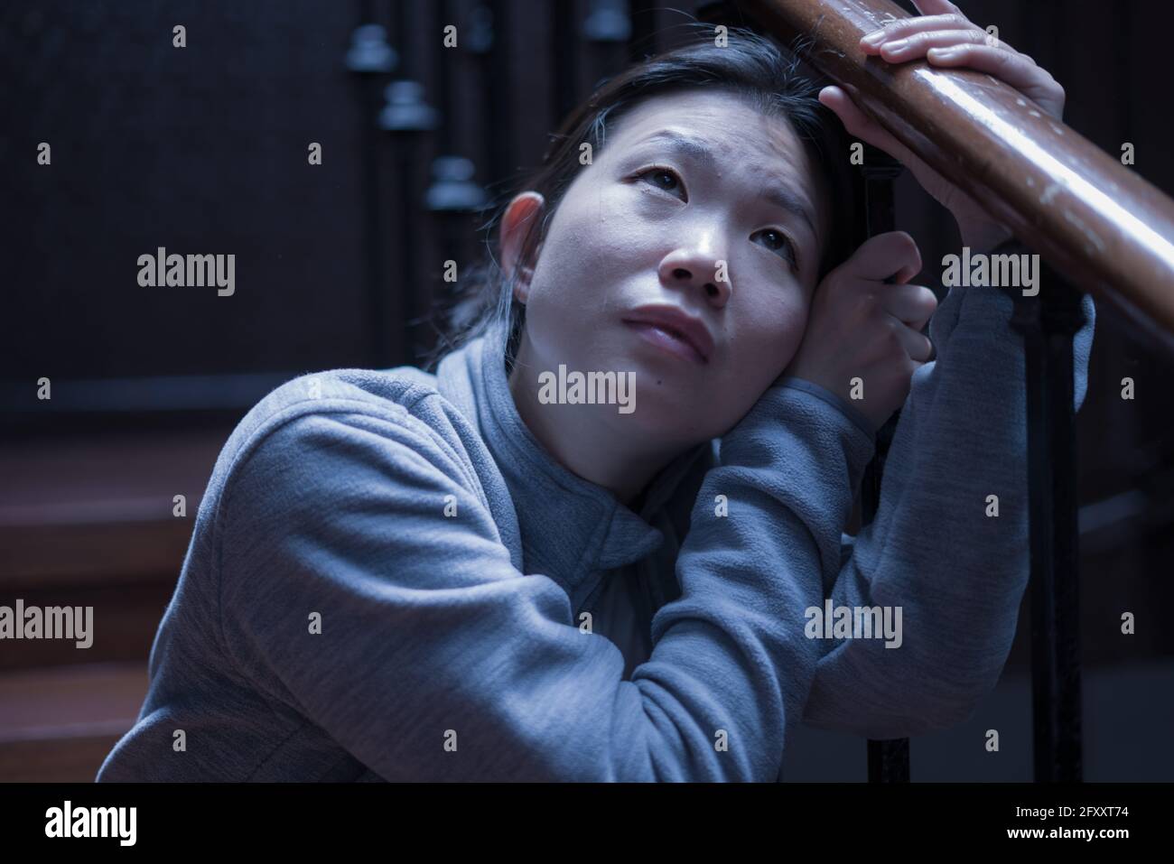 Jeune belle femme asiatique dans la douleur souffrant de dépression - dramatique Portrait à l'intérieur sur l'escalier d'une fille chinoise triste et déprimée comme victime de l'intimidation Banque D'Images