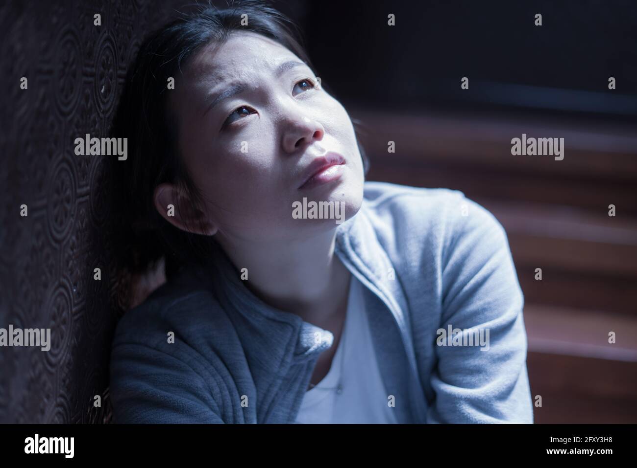 Jeune belle femme asiatique dans la douleur souffrant de dépression - dramatique Portrait à l'intérieur sur l'escalier d'une fille coréenne triste et déprimée comme victime de bullyi Banque D'Images