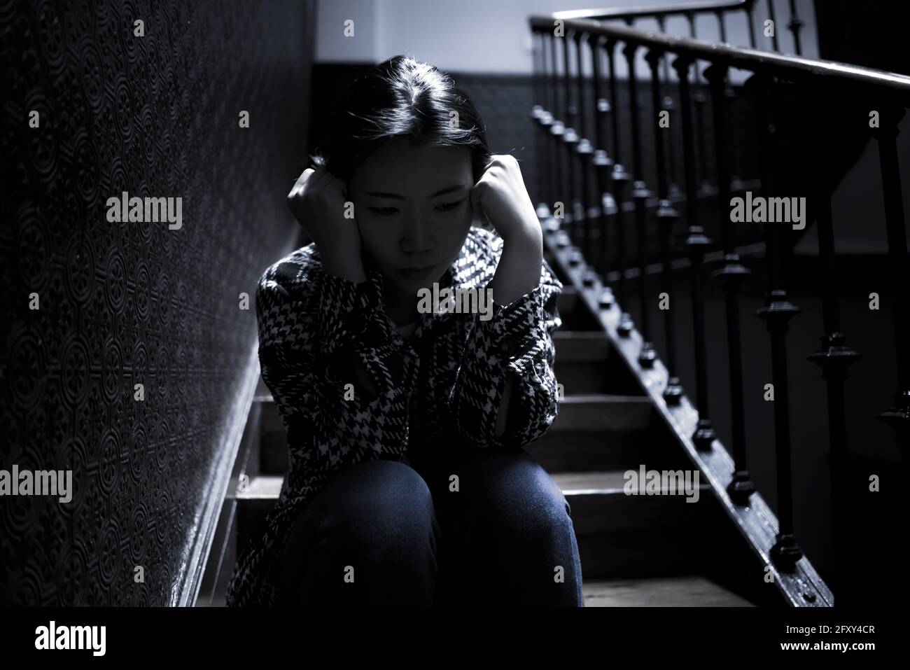Jeune belle femme asiatique dans la douleur souffrant de dépression - dramatique Portrait à l'intérieur sur l'escalier d'une fille coréenne triste et déprimée comme victime de bullyi Banque D'Images