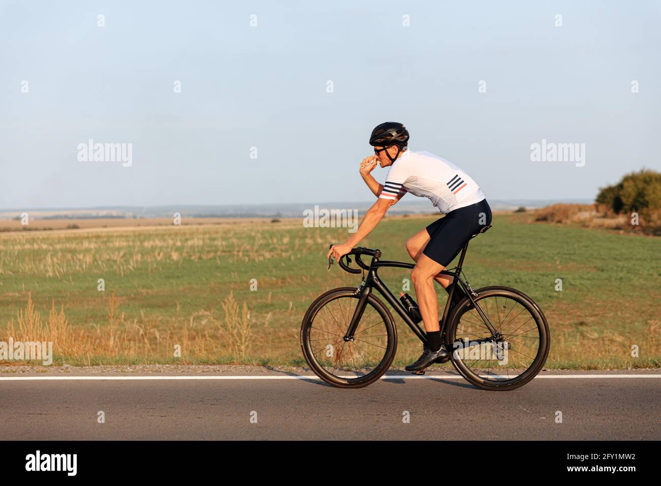 Homme sportif avec vélo musculaire sur route Banque D'Images