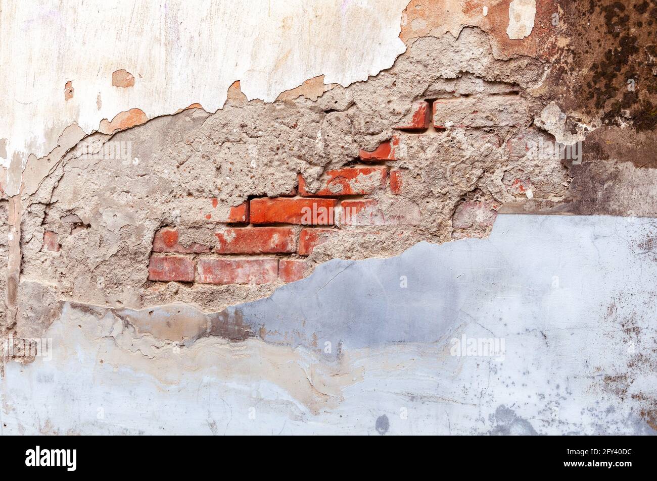 Murs en briques rouges rétro et grungeux avec stuc gris blanc cassé. Vue de la clôture en plâtre érodée et endommagée. Structure murale vintage avec plâtre Banque D'Images