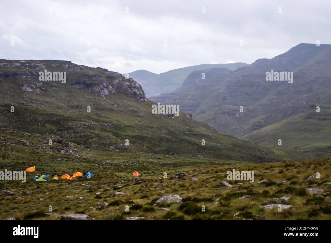 Un groupe de randonneurs aux couleurs vives se trouve dans une partie éloignée des montagnes du Haut Drakensberg, à la frontière entre l'Afrique du Sud et le Lesotho. Le rapide Banque D'Images