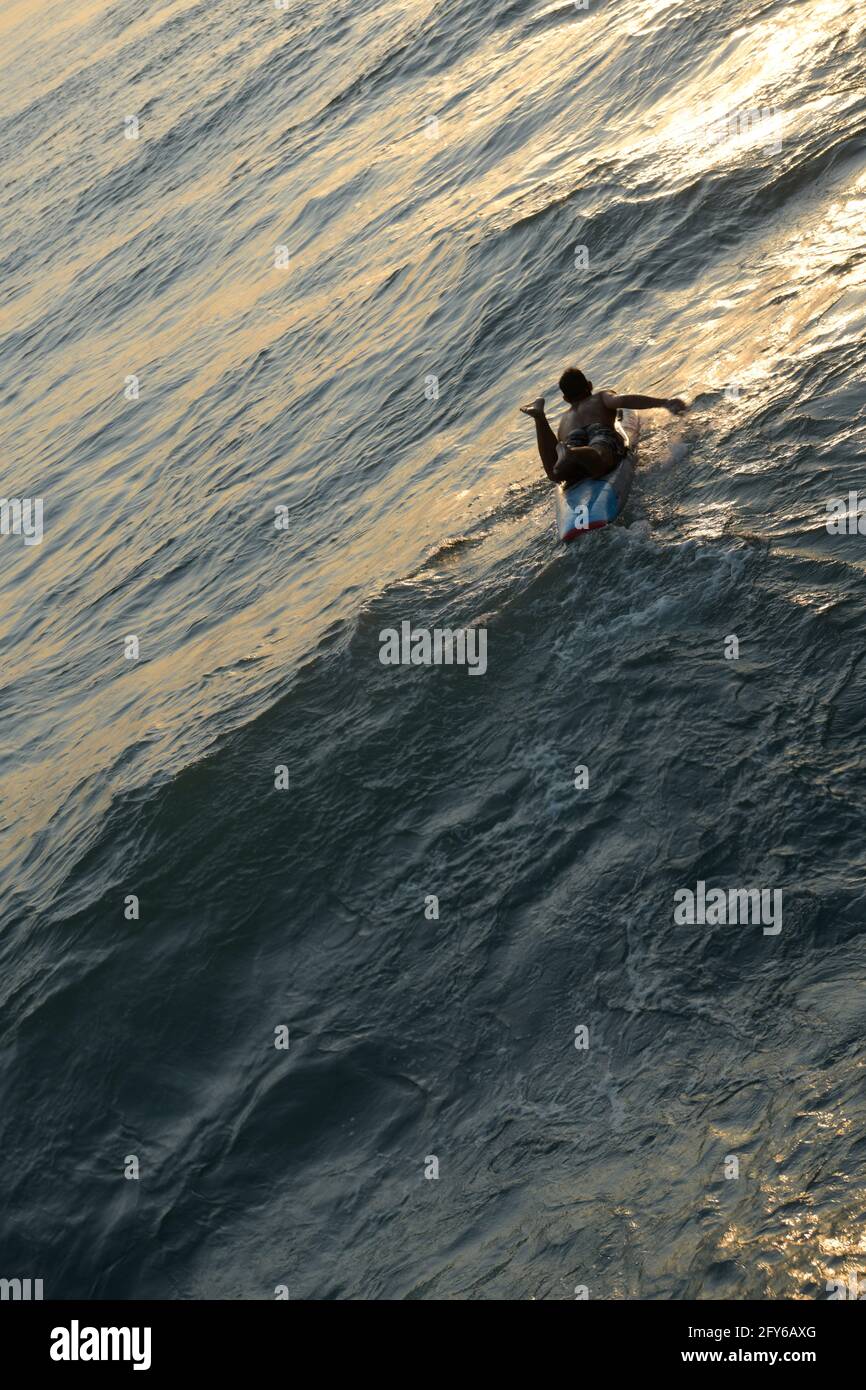 Mettre en place un jeune homme paddling paddle board pour surfer sur les vagues, Durban, Afrique du Sud, vie active, loisirs, sport, activité physique, exercice Banque D'Images