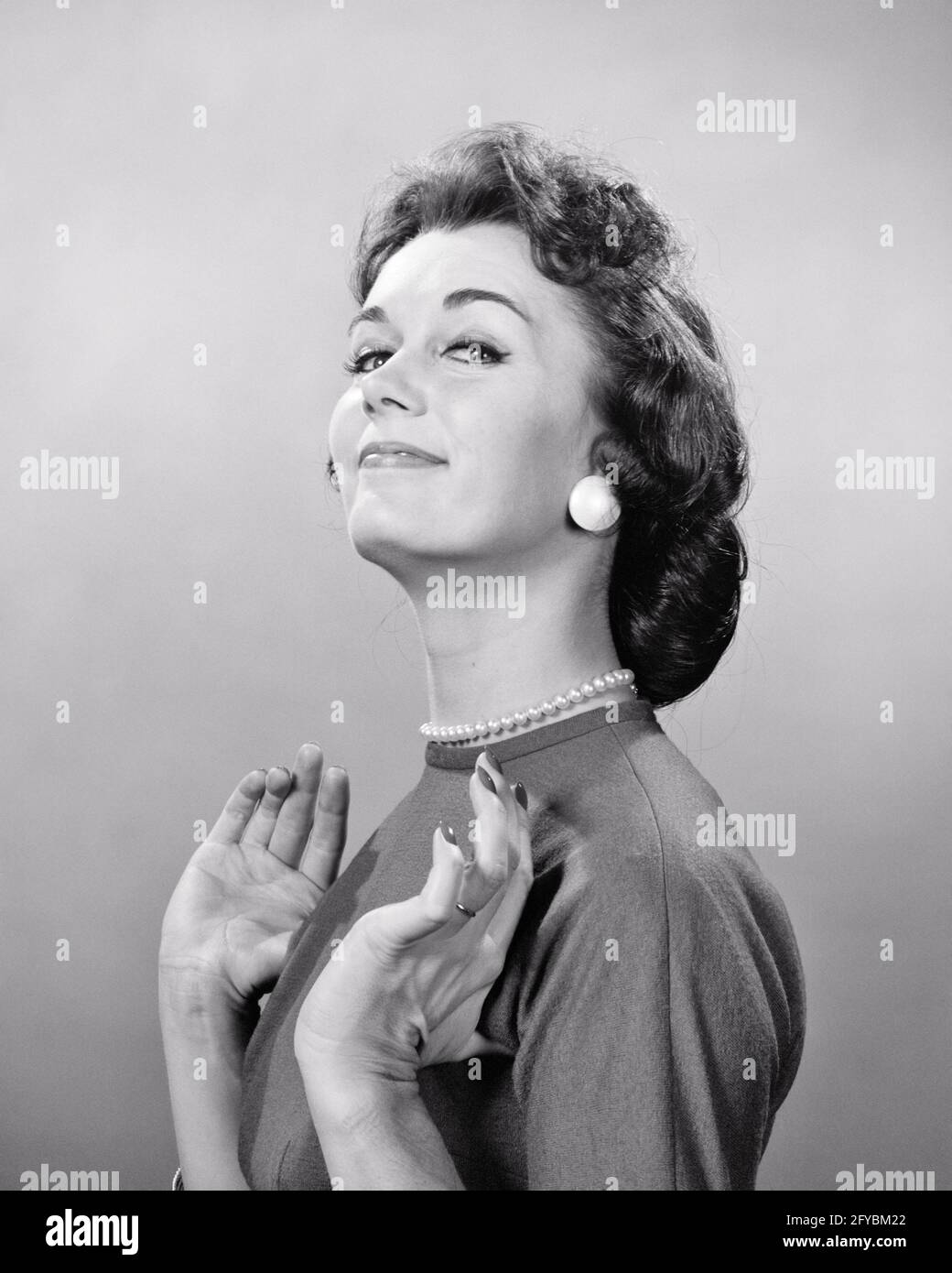 ANNÉES 1950, FEMME SOURIANTE PERLES BOUTON BOUCLES D'OREILLES DOIGTS  REPLIÉS SOUS ARMEZ FIÈREMENT L'EXPRESSION DU VISAGE SATISFAIT EN REGARDANT  L'APPAREIL PHOTO - G4865 HAR001 EXPRESSIONS HARS SMUG B&W CONTACT VISUEL  BRUNETTE SUCCÈS