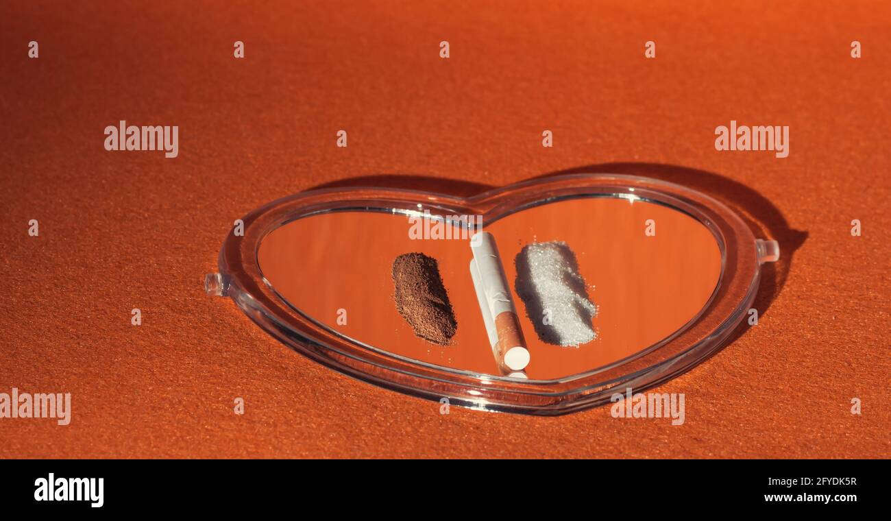 Gros plan de café de sucre et d'une cigarette sur un miroir en forme de coeur - le concept de mauvaises habitudes Banque D'Images