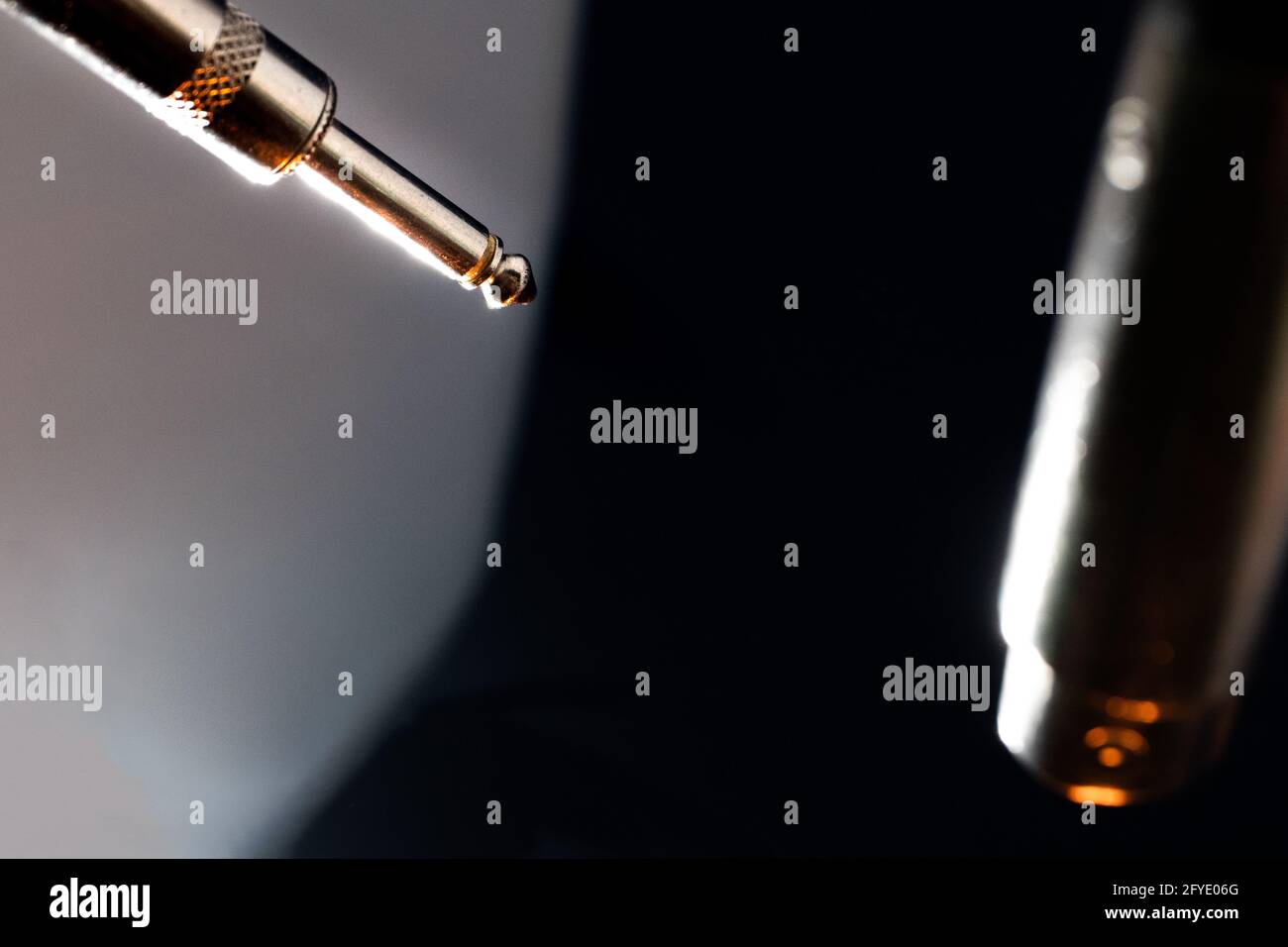 Résumé gros plan des extrémités sur le câble du microphone avec le quartier métallique Connecteur pouce à l'avant de l'arrière-plan blanc et connecteur XLR Devant le fond noir Banque D'Images