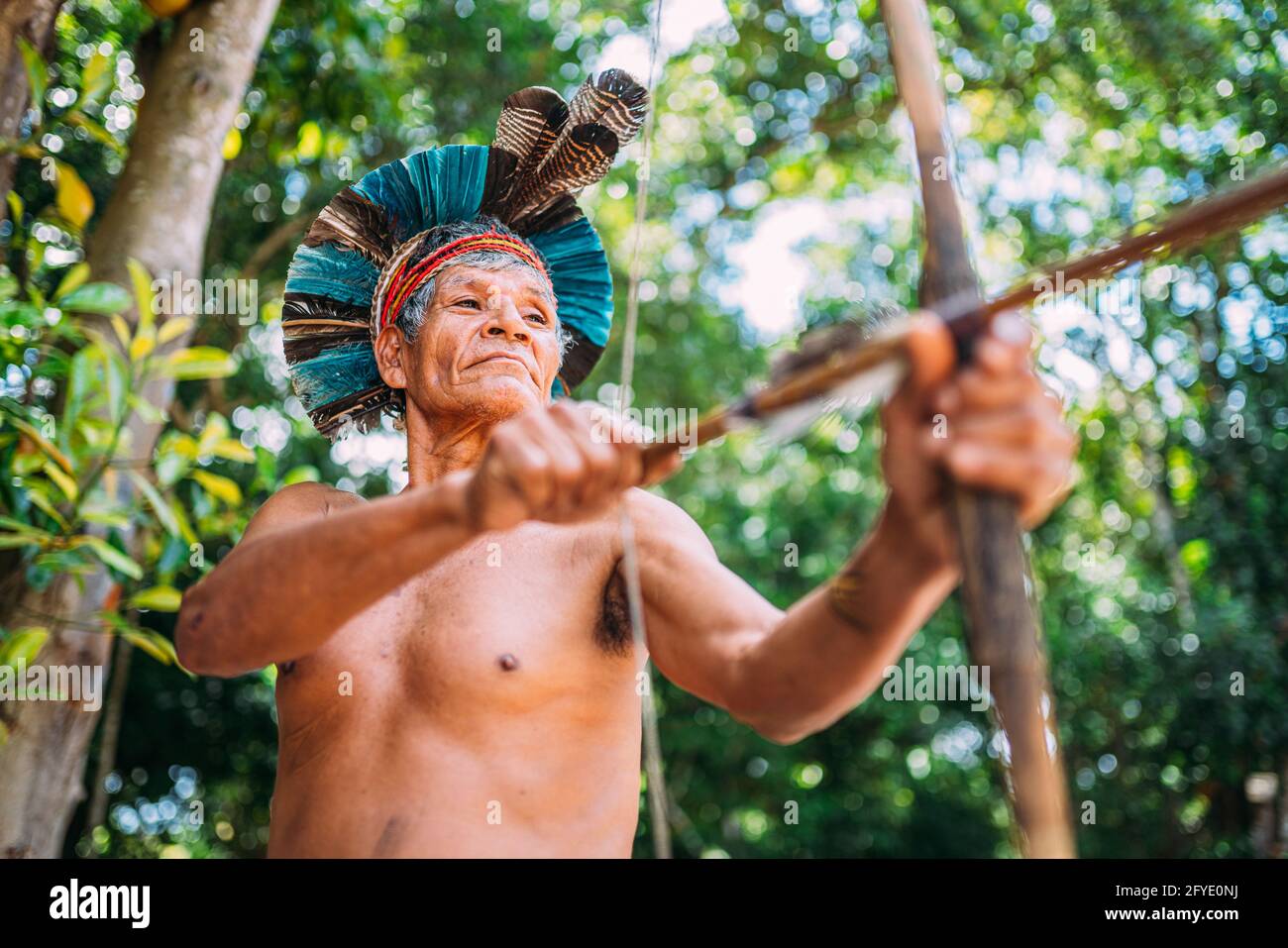 Indien de la tribu Pataxó, avec une plume de headaddress et d'arc et de flèche. Indien brésilien âgé regardant à droite. Banque D'Images