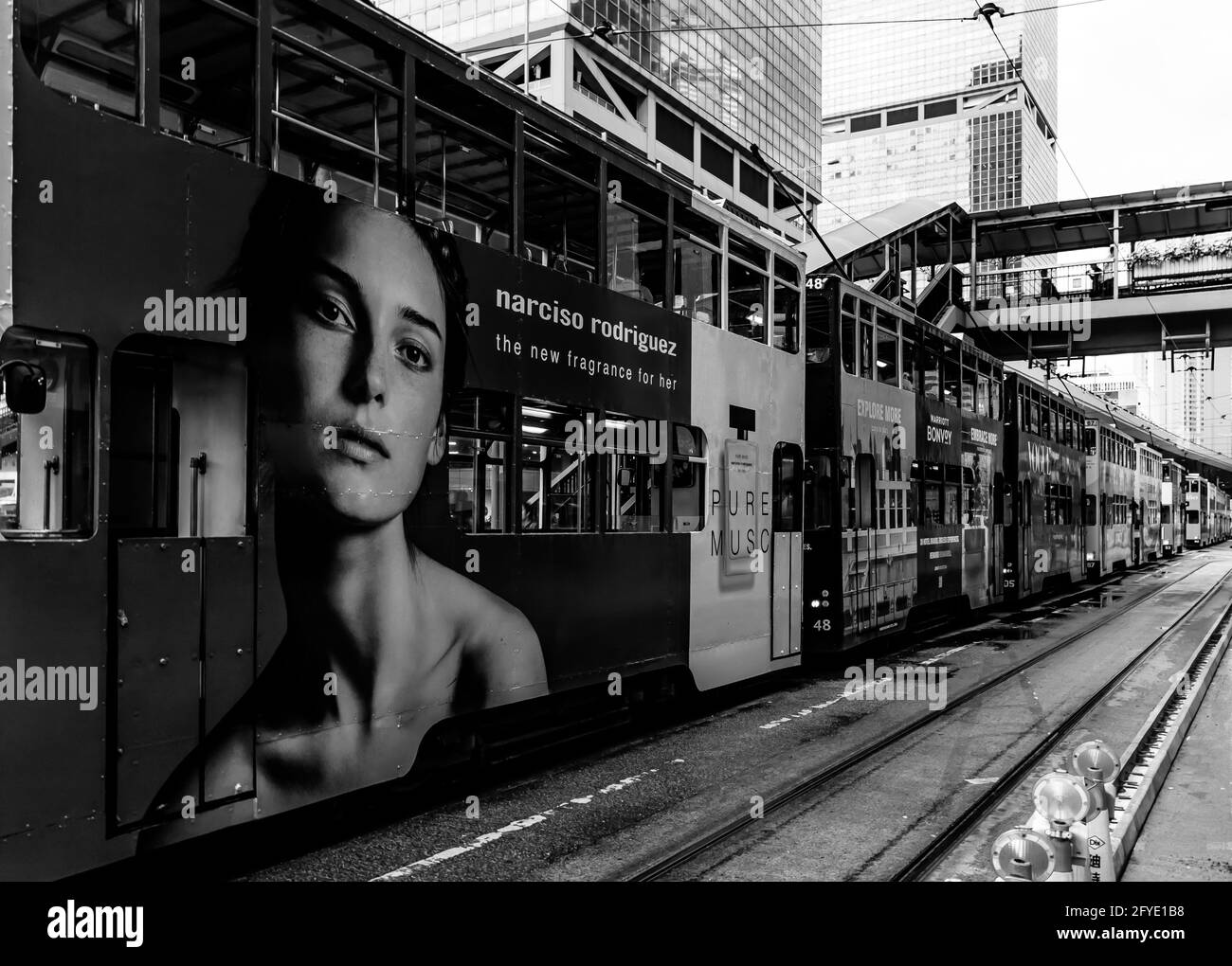 Une longue ligne de tramways attend en ligne après que de fortes pluies ont bloqué les lignes de tramway. Un tram porte une grande affiche publicitaire d'une femme. Banque D'Images