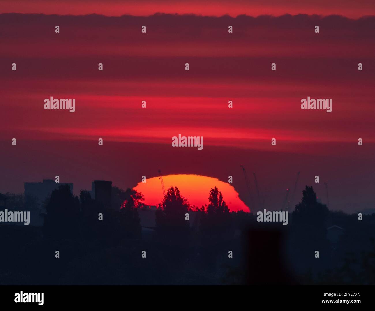 Wimbledon, Londres, Royaume-Uni. 28 mai 2021. Soleil orange profond au-dessus de Londres avant le début de la matinée, le nuage se déploie au début d'une journée douce dans la capitale. La légère tache d'un groupe de taches solaires est visible dans le quadrant supérieur droit du disque solaire. Crédit : Malcolm Park/Alay Live News. Banque D'Images