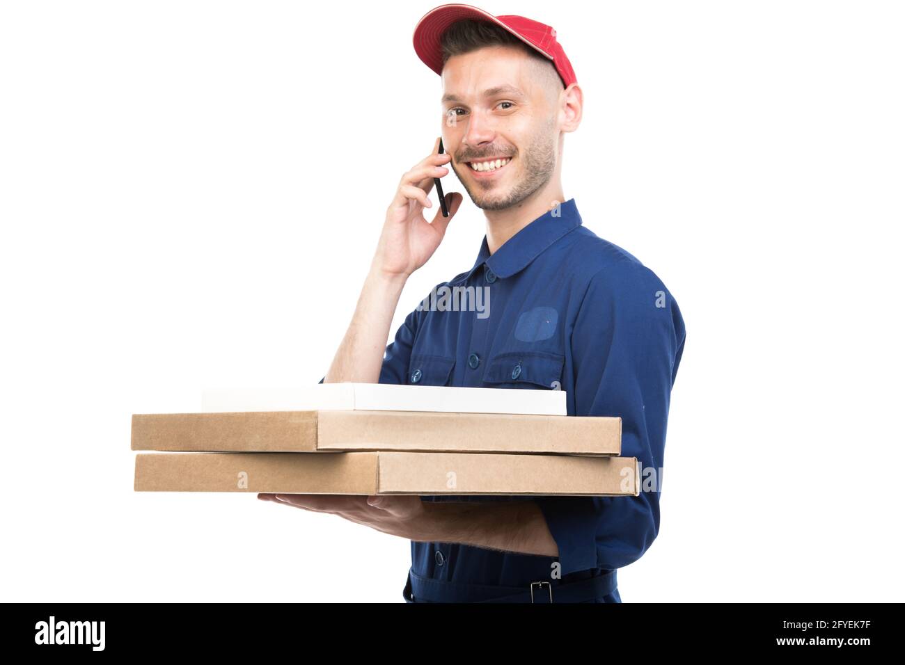 Portrait horizontal moyen d'un jeune adulte élégant de type de pizza caucasienne tenant des boîtes parlant au téléphone regardant l'appareil photo, fond blanc Banque D'Images