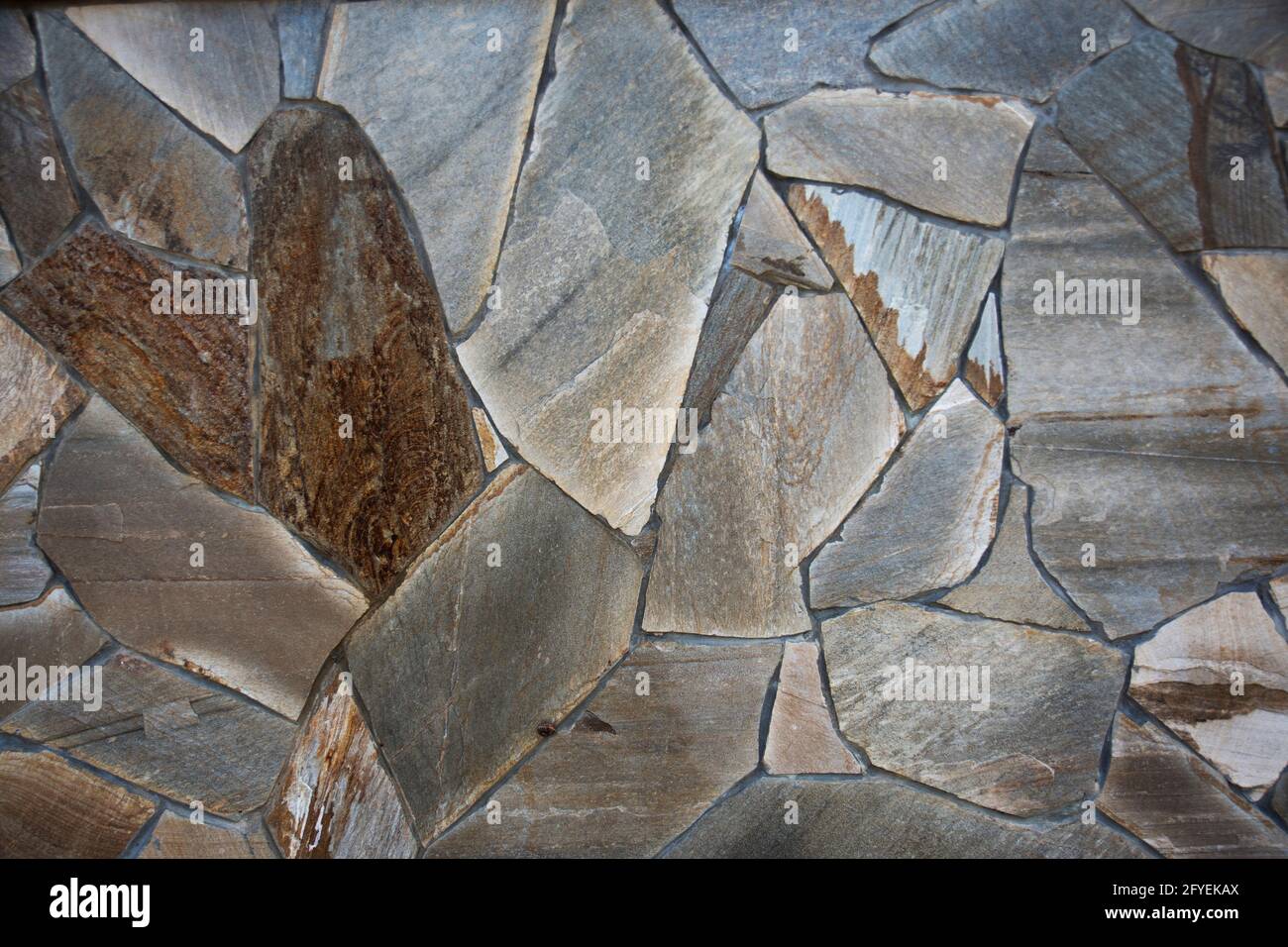 Photographie d'un vrai mur en pierres naturelles. mur de jardin avec un magnifique motif asymétrique de mosaïque Banque D'Images