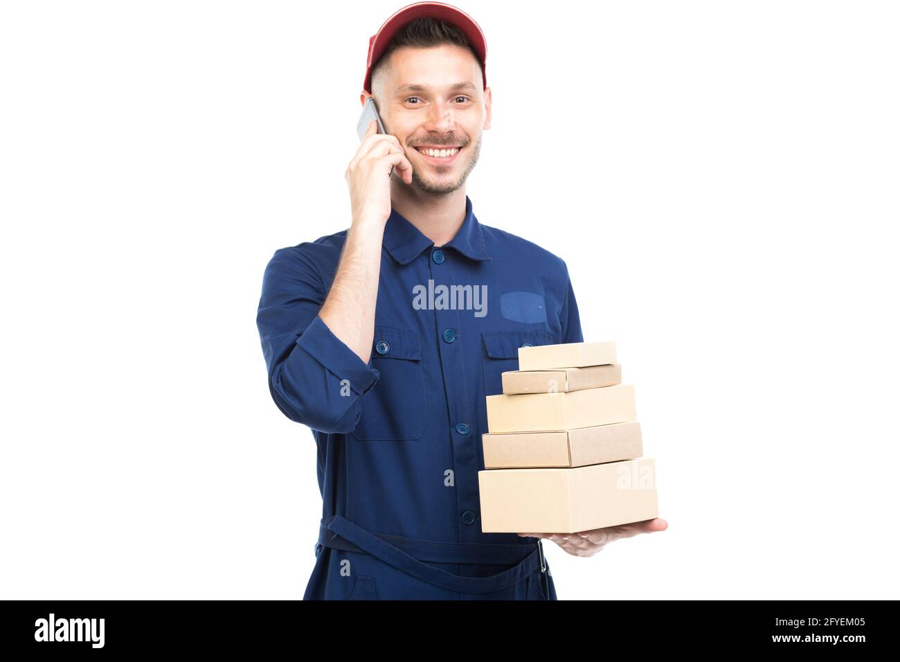 Portrait horizontal moyen d'un jeune adulte élégant de race blanche liveur portant des boîtes de maintien bleu uniforme à l'aide d'un smartphone, fond blanc Banque D'Images