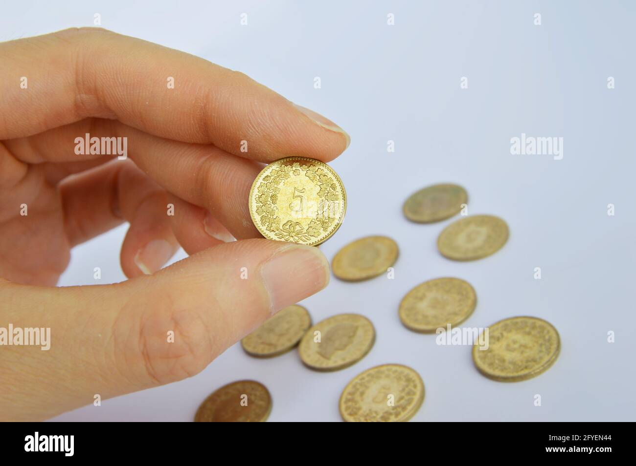 Main courte tenant une pièce de monnaie suisse de 5 cents sur fond blanc Banque D'Images