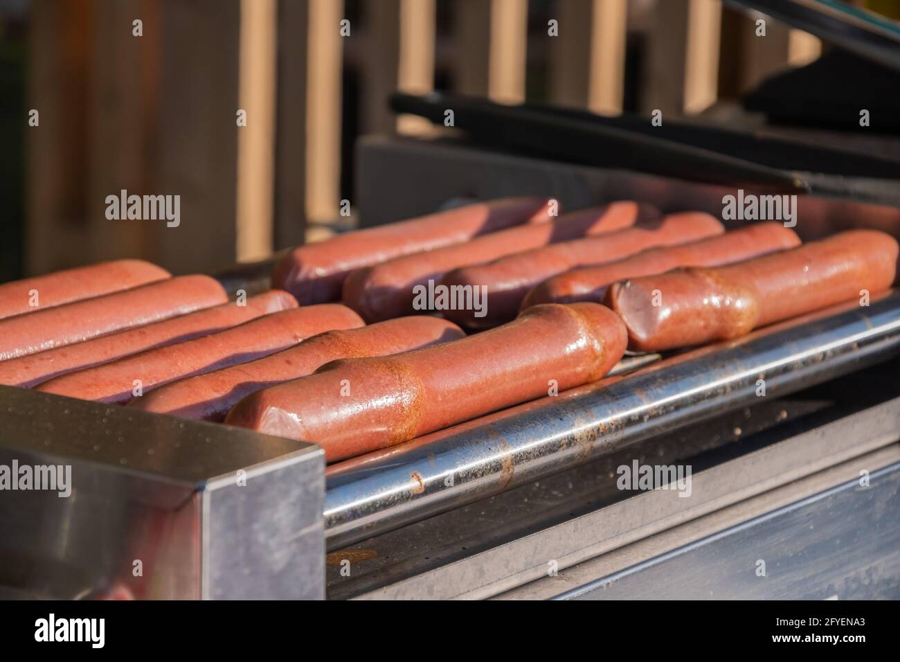 Les saucisses de hot dog sont frites sur une machine de cuisson rotative dans un café extérieur Banque D'Images