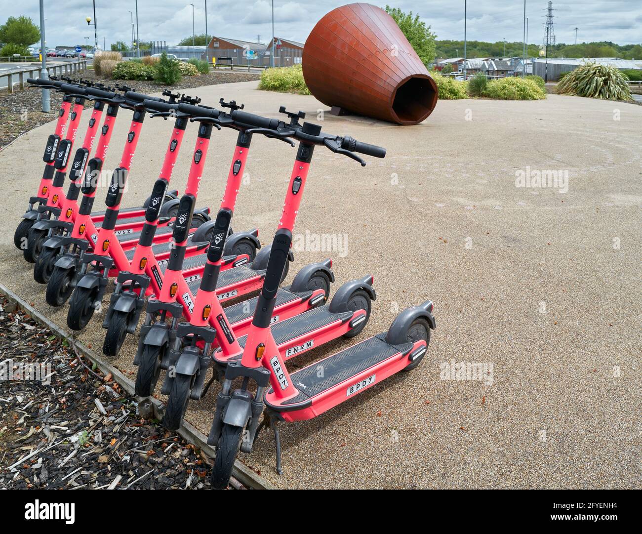 Ligne nette de scooters électriques garés (e-trottinettes) à l'extérieur du supermarché Tesco, Corby, Angleterre. Banque D'Images